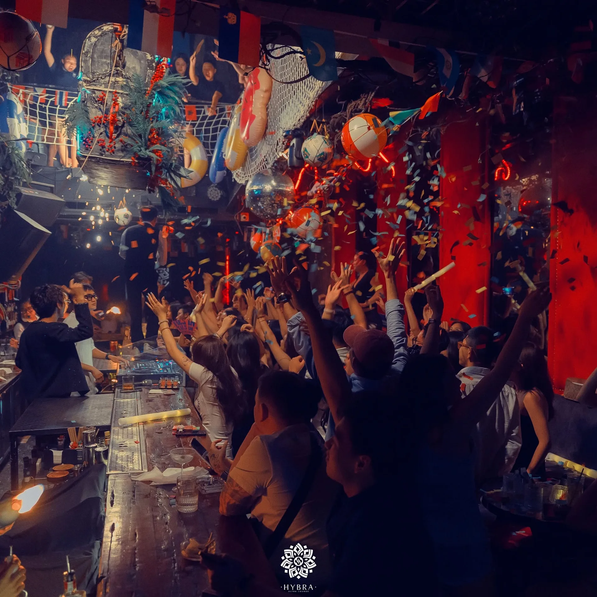 Lưới đánh cá, phao cứu sinh và bóng bãi biển treo trên trần giữa mưa pháo giấy tại HYBRA Ultra Lounge