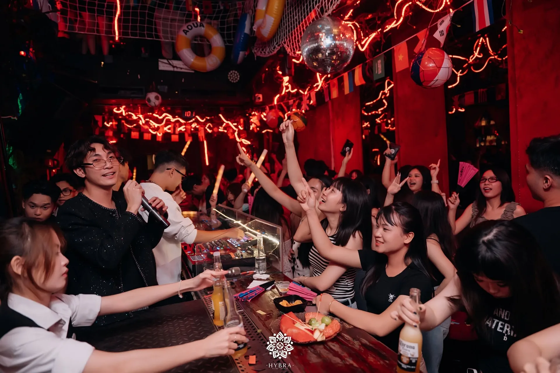 Trần lưới treo phao, quả cầu disco và dây đèn đỏ uốn lượn tại HYBRA Ultra Lounge Hà Nội